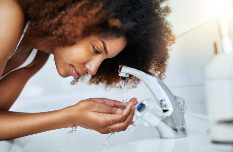 Woman-Looking-At-Water-From-Bathroom-Sink